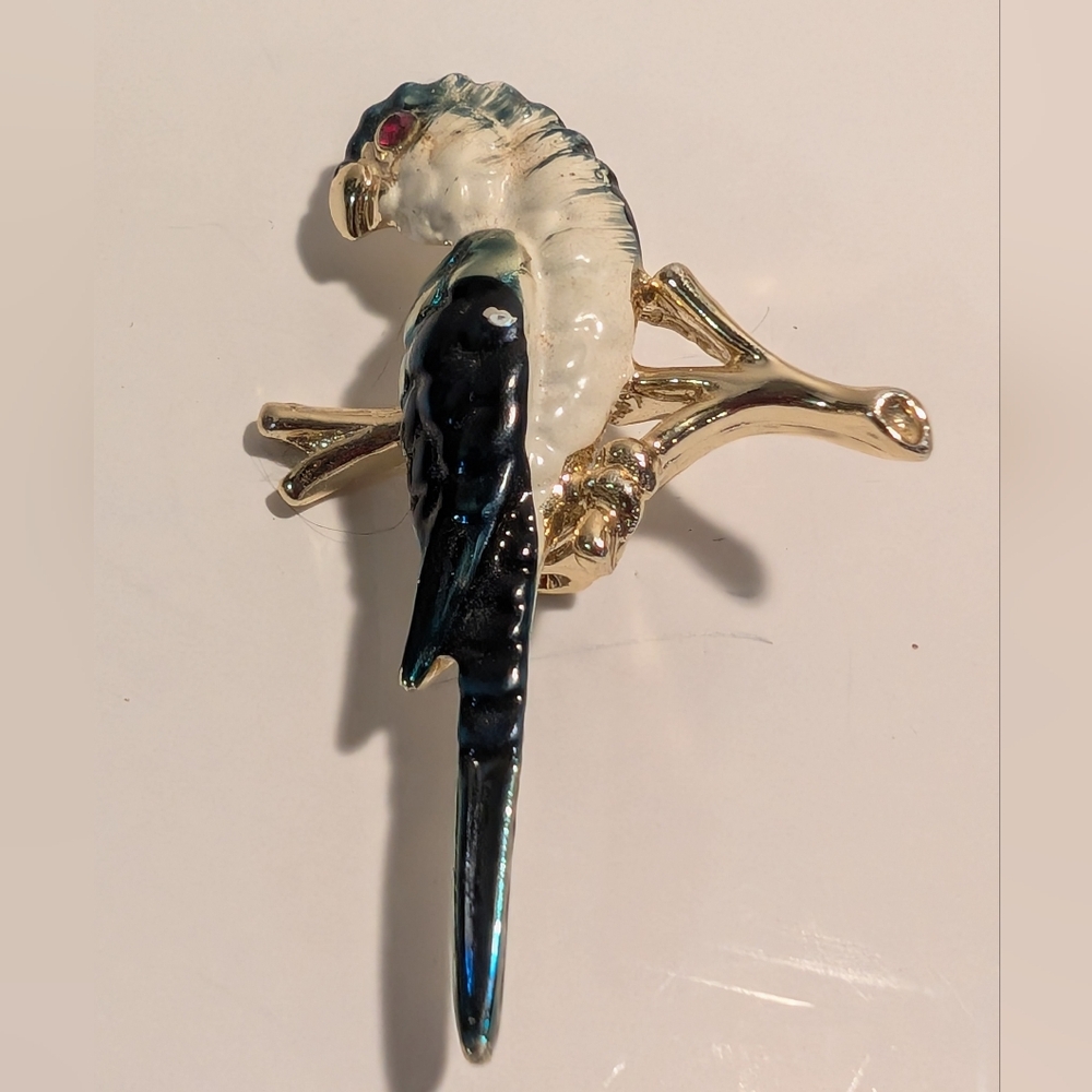A vintage gold-tone, blue and white enamel parrot brooch with a red rhin